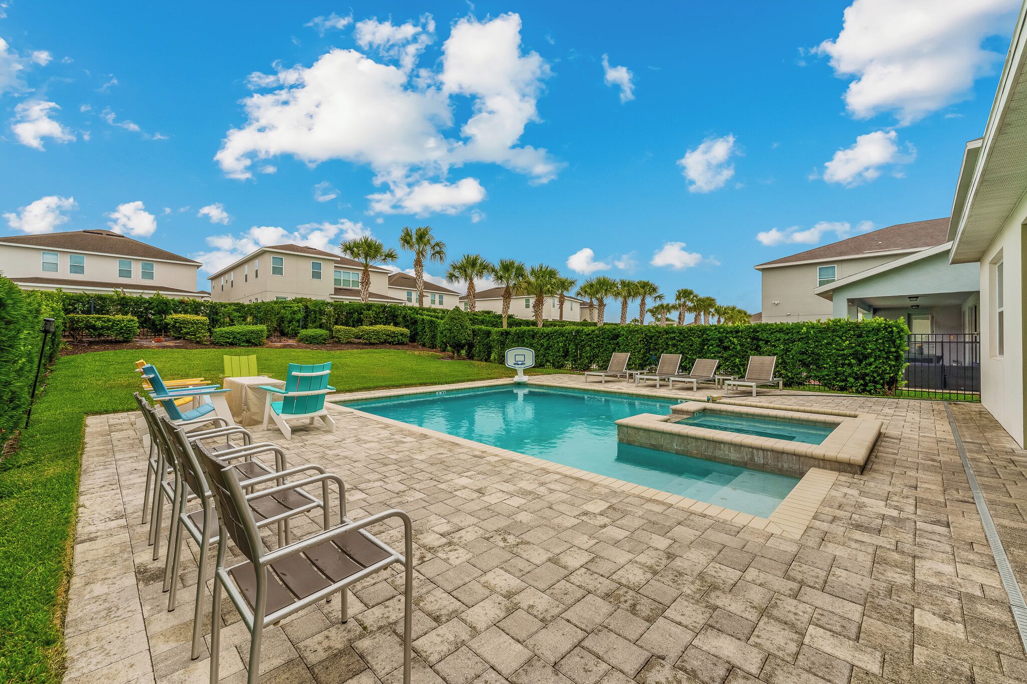 A backyard with a swimming pool, lounge chairs, and a small table.