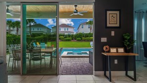 A modern interior with a sliding glass door leading to a patio with a pool, outdoor furniture, and a ceiling fan. - 5BR Gorgeous Villa • Spiderman • Near Disney (Kissimmee)