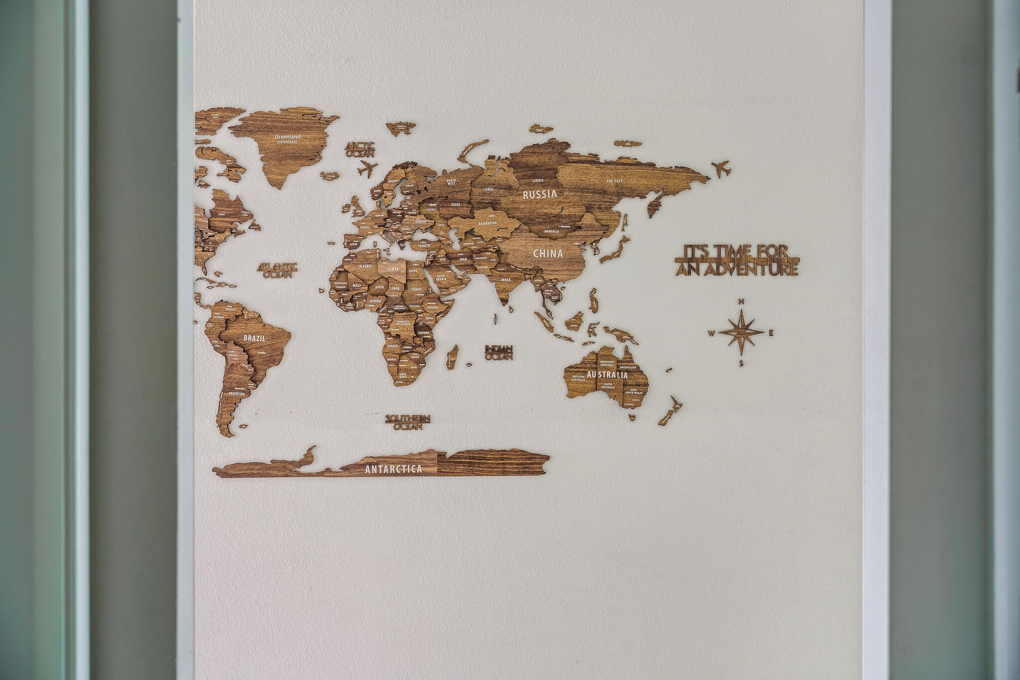 Un mapa mundial de madera con nombres de países y una rosa de los vientos.