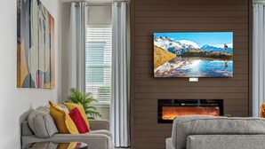 A modern living room with a large flat-screen TV, a fireplace, and a sofa with colorful cushions. - 5BR Gorgeous Villa • Spiderman • Near Disney (Kissimmee)