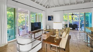 A spacious living area with a large TV, comfortable seating, and a view of greenery outside.