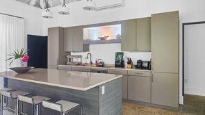 A modern kitchen with a central island, stainless steel appliances, and a dining area with bar stools.