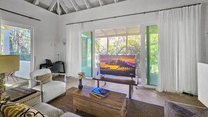 A spacious living room with a large window, a flat-screen TV, a comfortable sofa, and a wooden coffee table.
