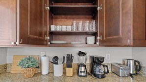 Eine Küche mit Holzausstattung, einer Arbeitsplatte aus Granit, einer Kaffeemaschine, einem Toaster und einem Mixer.