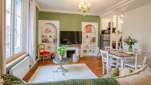 A cozy living room with a fireplace, a television, and a dining area with chairs and a table. - L'Ecrin de la Cathédrale (TROYES)