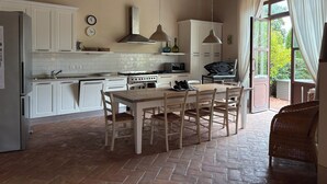 Una cocina con armarios blancos, una estufa y una mesa de comedor con sillas.