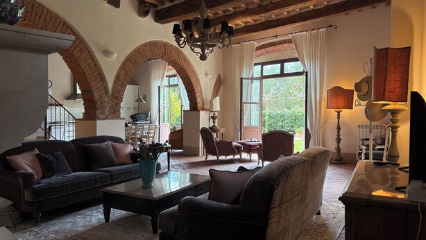 Amplia sala de estar con chimenea, asientos cómodos y vista al jardín.