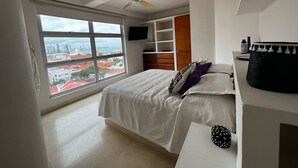 Un dormitorio moderno con un ventanal grande, una cama, un ventilador de techo y estanterías empotradas.