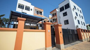 A modern residential building with a gated entrance, multiple balconies, and a clear blue sky. - Executive Two Bedroom Furnished Apartment (Accra)