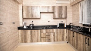 A modern kitchen with wooden cabinets, a black countertop, and a built-in stove. - Executive Two Bedroom Furnished Apartment (Accra)