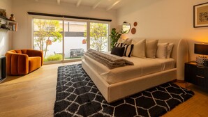 A modern bedroom with a large bed, a sofa, and a TV. - Hauser House, Modern Artful Spanish-style Bungalow (Los Angeles)