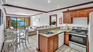 A modern kitchen with a dining area, large windows, and a view of the outdoors. - Newly Remodeled Flamingo Condo with Sweeping Ocean Views, Spacious Terrace & Walkable Location (Cabo Velas)