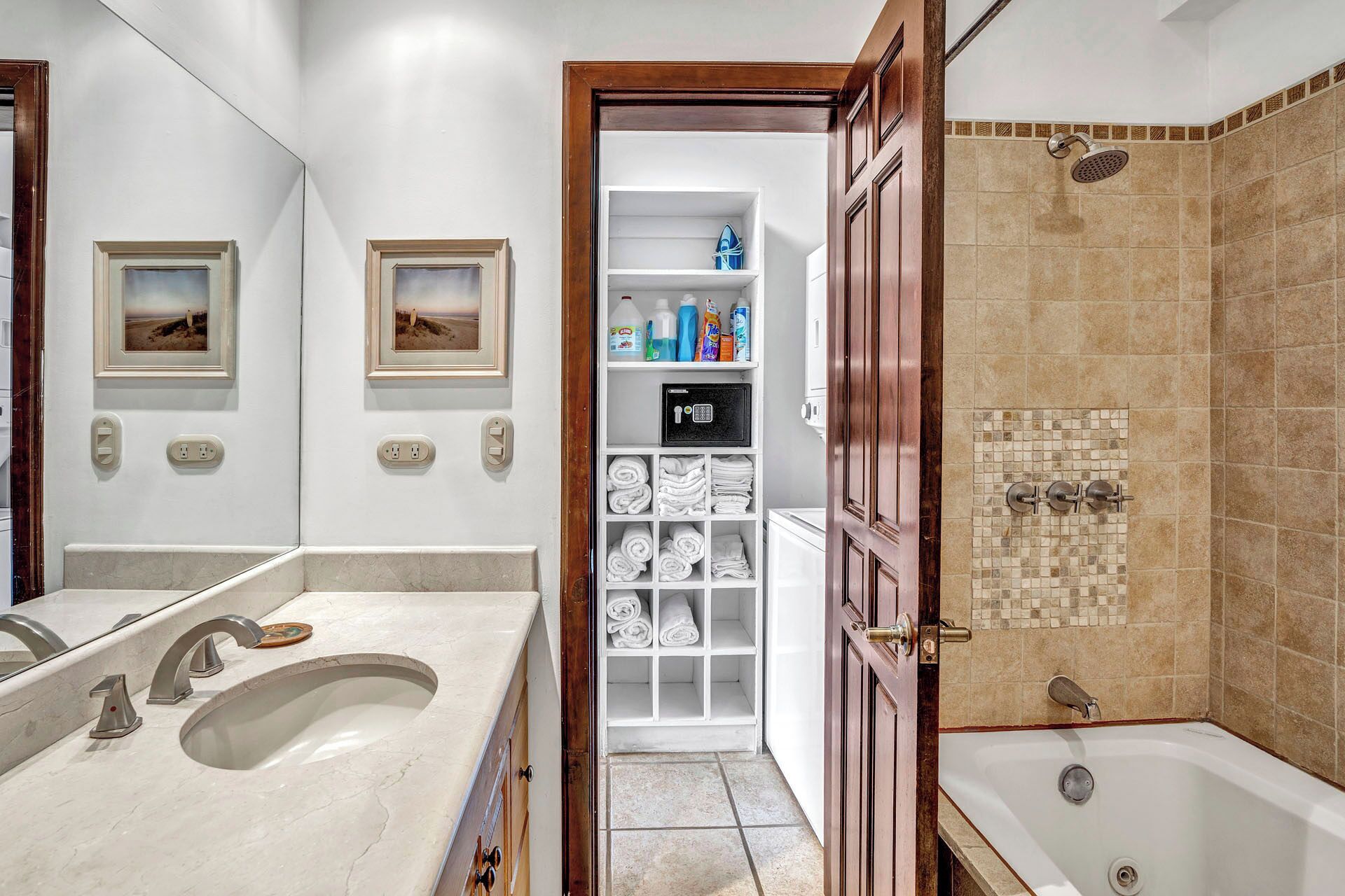 A bathroom with a large mirror, two sinks, a walk-in shower, and a storage closet with shelves.