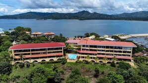 A hotel with multiple buildings, a swimming pool, and a view of a lake and mountains. - Newly Remodeled Flamingo Condo with Sweeping Ocean Views, Spacious Terrace & Walkable Location (Cabo Velas)