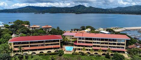 A hotel with multiple buildings, a swimming pool, and a view of a lake and mountains.