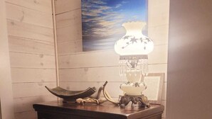 A wooden dresser with a lamp, a framed picture, and a small table with a bowl and a spoon. - Sea la Vie - Margaree farmhouse by river and sea! (Margaree Harbour)
