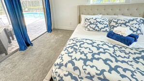 A bedroom with a large bed, a view of a pool, and a sliding glass door. - LE BLEU Charming Poolside Retreat/Close to beach (Bonita Springs)