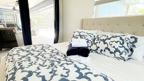 A bedroom with a bed, a headboard, a window with blinds, and a view of the outside. - LE BLEU Charming Poolside Retreat/Close to beach (Bonita Springs)