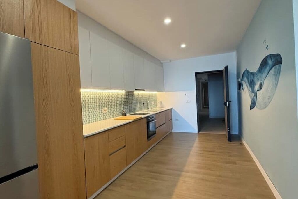 A modern kitchen with wooden cabinets, a tiled backsplash, and a stainless steel refrigerator.