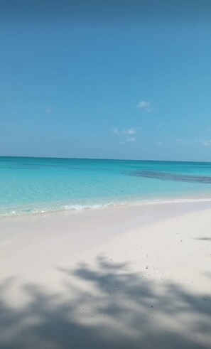 Een strand met helder turquoise water en wit zand.