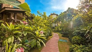 Un sentier de jardin mène à un bâtiment doté d’une façade en pierre et d’un auvent vert.