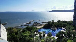 Un complexe hôtelier doté d’une piscine entourée de palmiers et offrant une vue sur la mer.