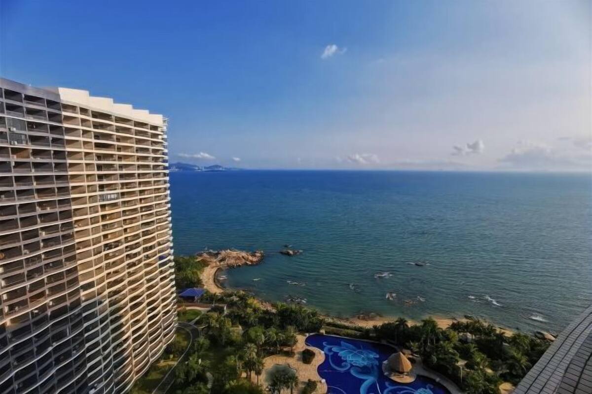 A high-rise hotel with a pool area and a view of the sea.