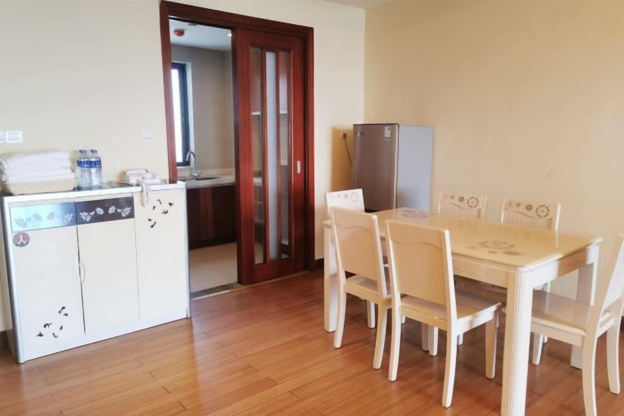 A compact kitchen with a dining table and chairs, a refrigerator, and a water dispenser.