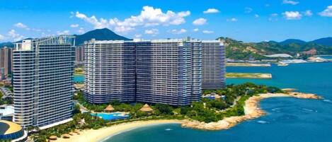 Un hotel moderno de gran altura con varios pisos, situado cerca de una playa y rodeado de agua.
