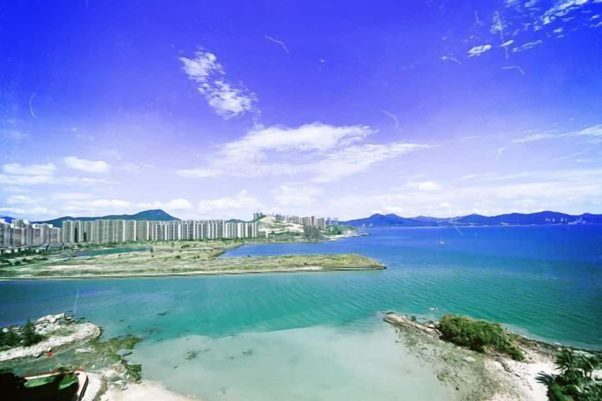 A coastal cityscape with high-rise buildings, a marina, and a clear blue sky.