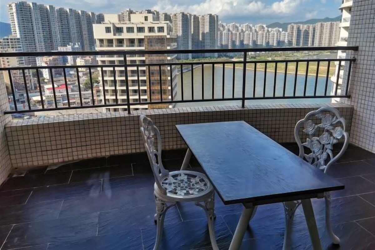 A balcony with a table and chairs, a view of high-rise buildings, and a tiled floor.