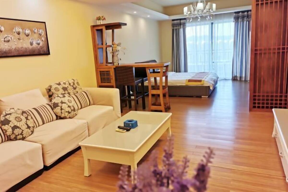 A modern living room with a sofa, a coffee table, a desk, and a bed.