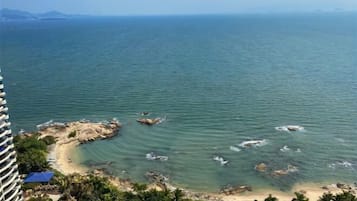 Eine Küstenansicht mit Strand, klarem Wasser und Bergen in der Ferne.