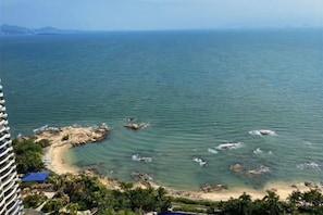 A coastal view with a beach, clear water, and distant mountains. - Genting Coast Resort Apartment (Huidong Country Garden Shili Yintan Branch) (Huidong)