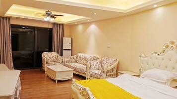 A hotel room with a bed, a sofa, a coffee table, and a ceiling fan.