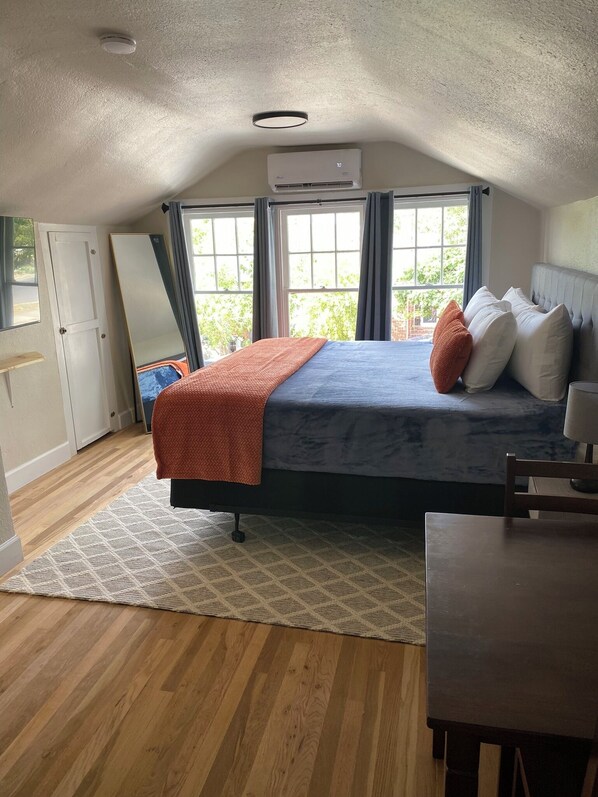 Relax in this inviting bedroom with a large bed, air conditioning, and natural light pouring in through the windows.