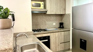 Une cuisine moderne dotée de plans de travail en granit, d’appareils électroménagers en acier inoxydable et de meubles en bois.