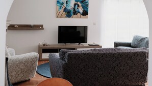 A modern living room with a sofa, TV, and dining area.
