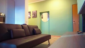 A modern living room with a sofa, a round mirror, and a door leading to another room.