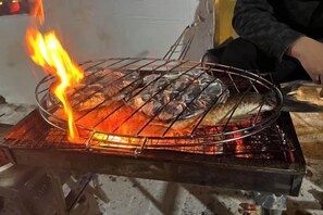 A grill with fish being cooked over an open flame. - Ningbo Ivory Guest Youth Hostel (Ningbo)