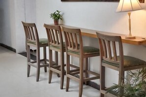 A dining area with a wooden table and four chairs, a potted plant, and a lamp on a wall-mounted shelf. - Ningbo Ivory Guest Youth Hostel (Ningbo)