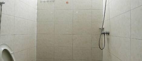 A small, tiled shower stall with a handheld showerhead and a toilet.