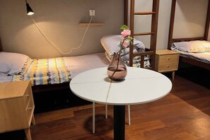 A cozy bedroom with a bed, bedside table, lamp, and a small round table with a vase. - Ningbo Ivory Guest Youth Hostel (Ningbo)