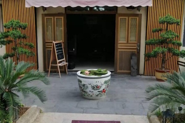 A traditional building entrance with a large potted plant, wooden doors, and a signboard. - Ningbo Ivory Guest Youth Hostel (Ningbo)