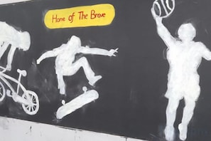 Un muro con grafitis que muestran a una persona practicando skate y a otra jugando tenis.