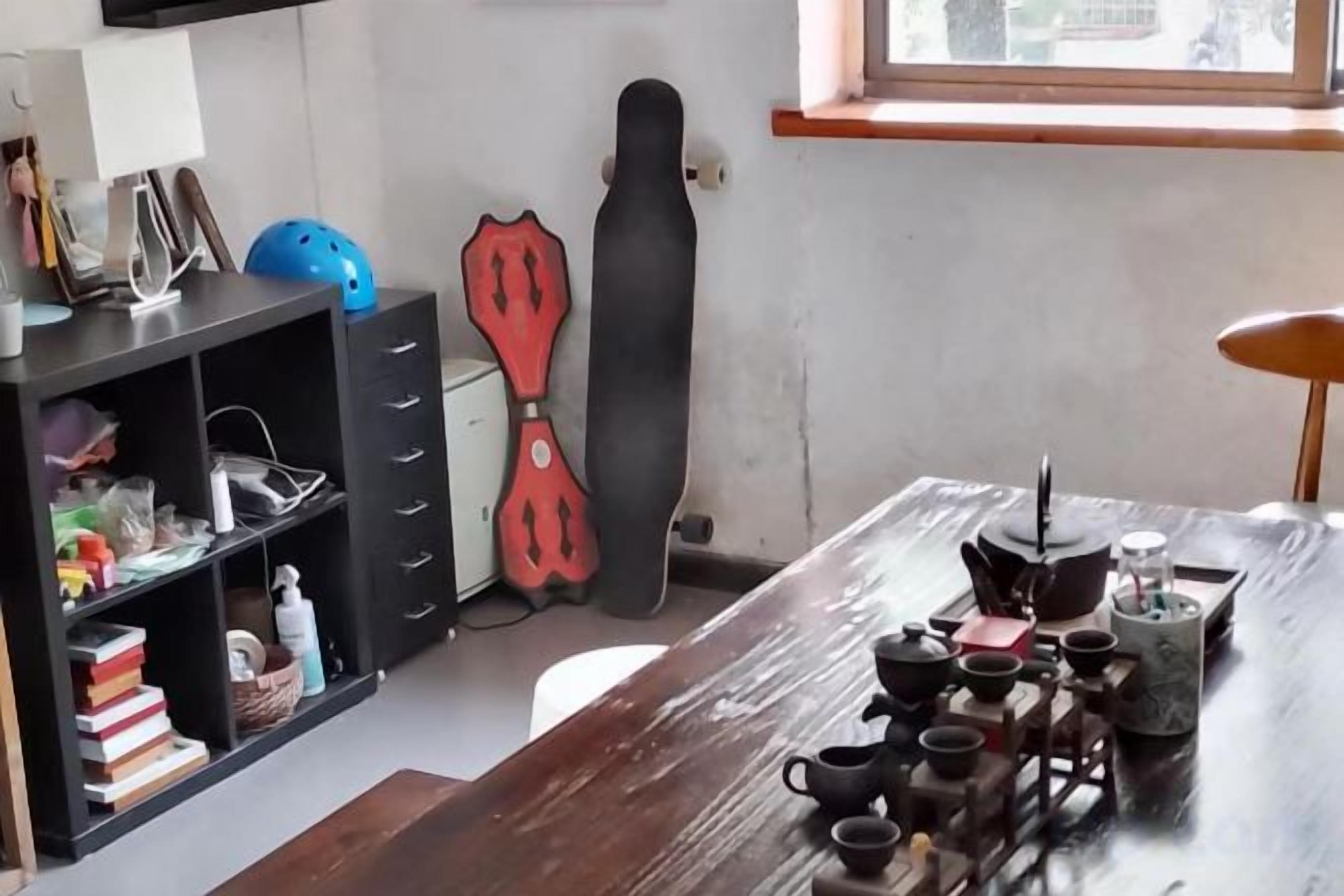 A kitchen with a wooden table, a red guitar, and a black cabinet with drawers.