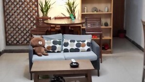 A living room with a sofa, a coffee table, a teddy bear, and a bookshelf. - Ningbo Ivory Guest Youth Hostel (Ningbo)