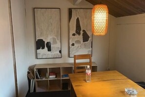 A dining area with a wooden table, a chair, a bottle, and a hanging light fixture. - Ningbo Ivory Guest Youth Hostel (Ningbo)