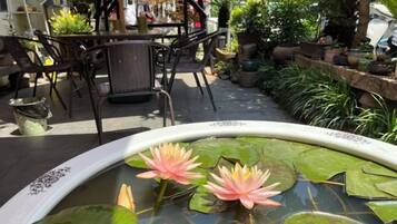 A pond with water lilies and a dining area with chairs and tables.