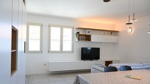 Una sala de estar moderna con sofá, televisión y comedor.